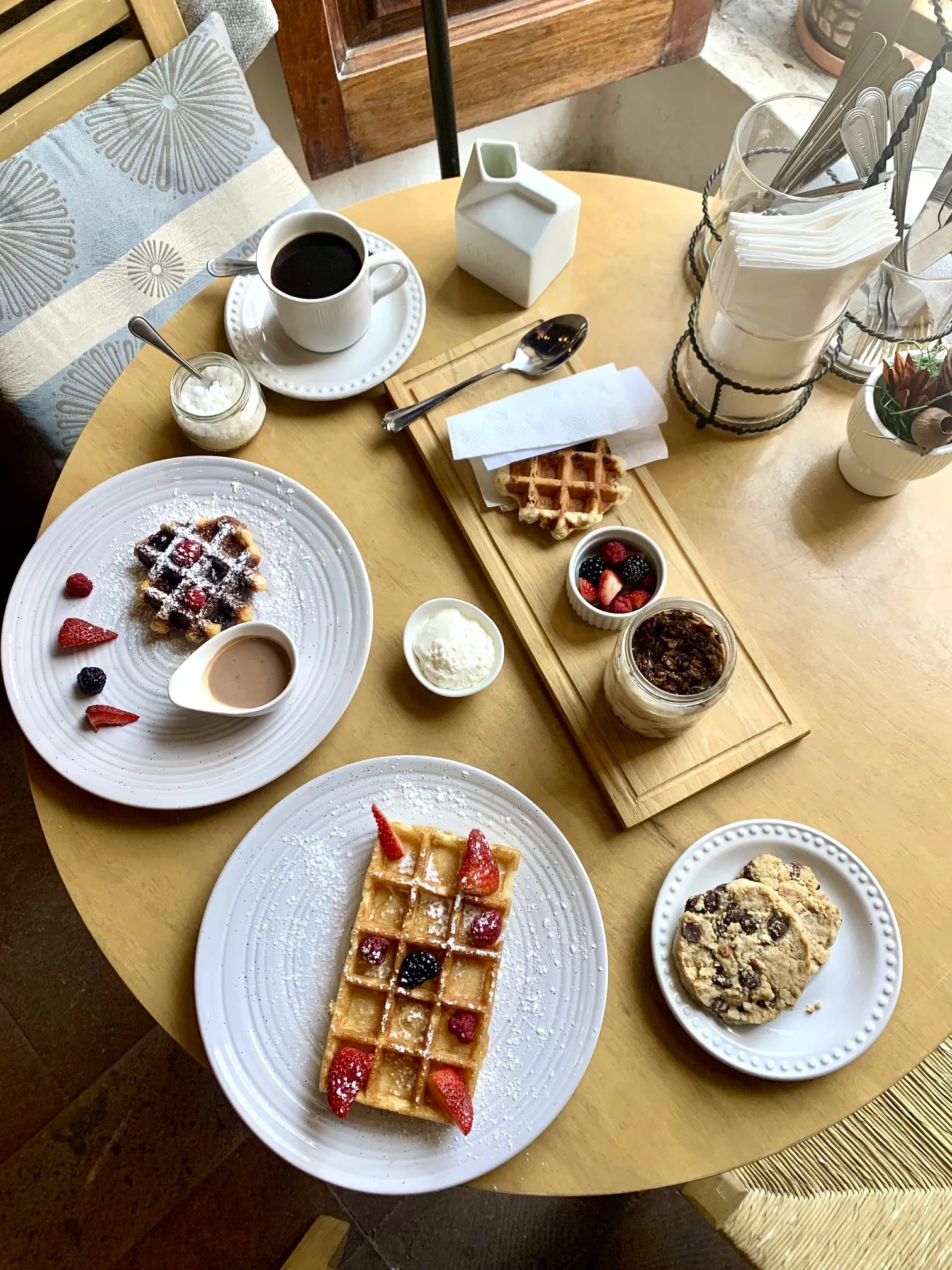 Mesa vista desde arriba con waffles, café, fruta y chocolate belga